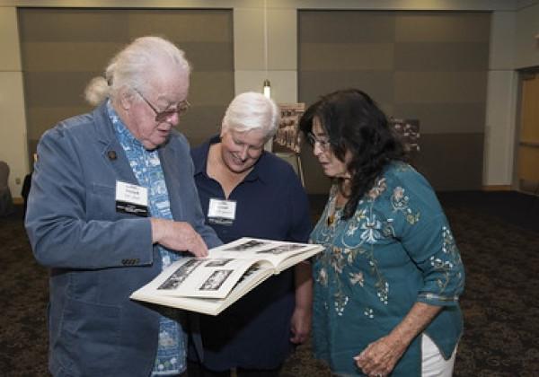 Three alumni from the class of 1972 look over a yearbook